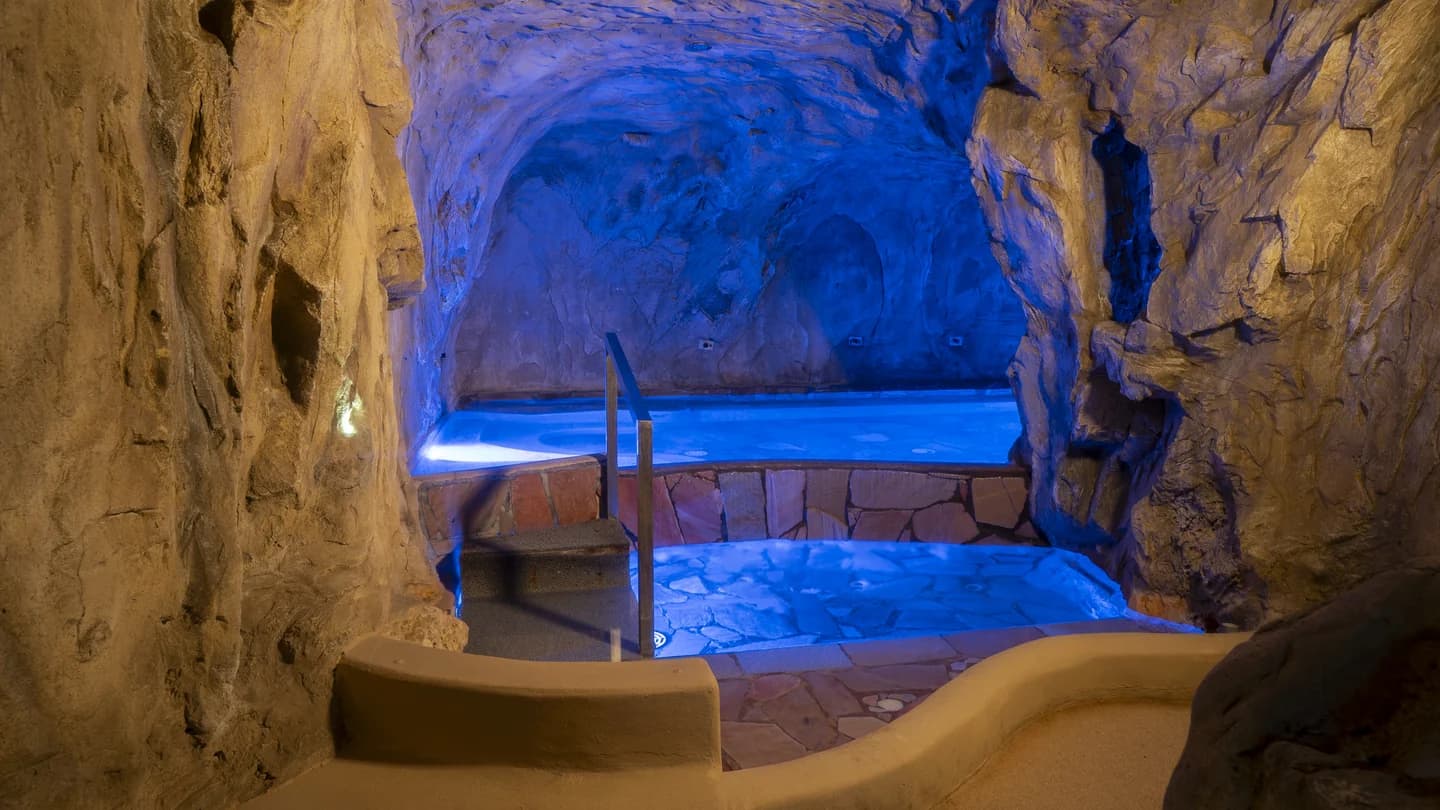 Area benessere New Way Fitness con vasca idromassaggio in ambiente roccioso illuminato